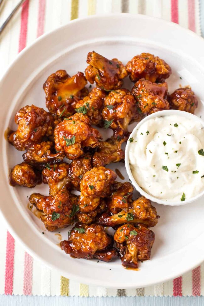 Sticky BBQ cauliflower wings served in a bowl with sour cream dip.