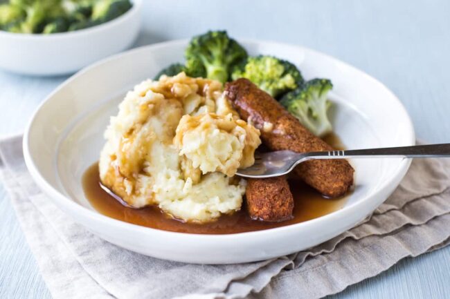 Bangers and mash being eaten with a fork.