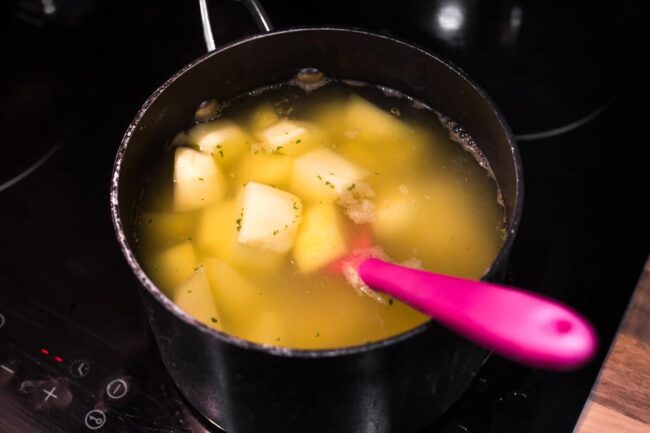 Chopped potatoes cooking in a pan of hot water.