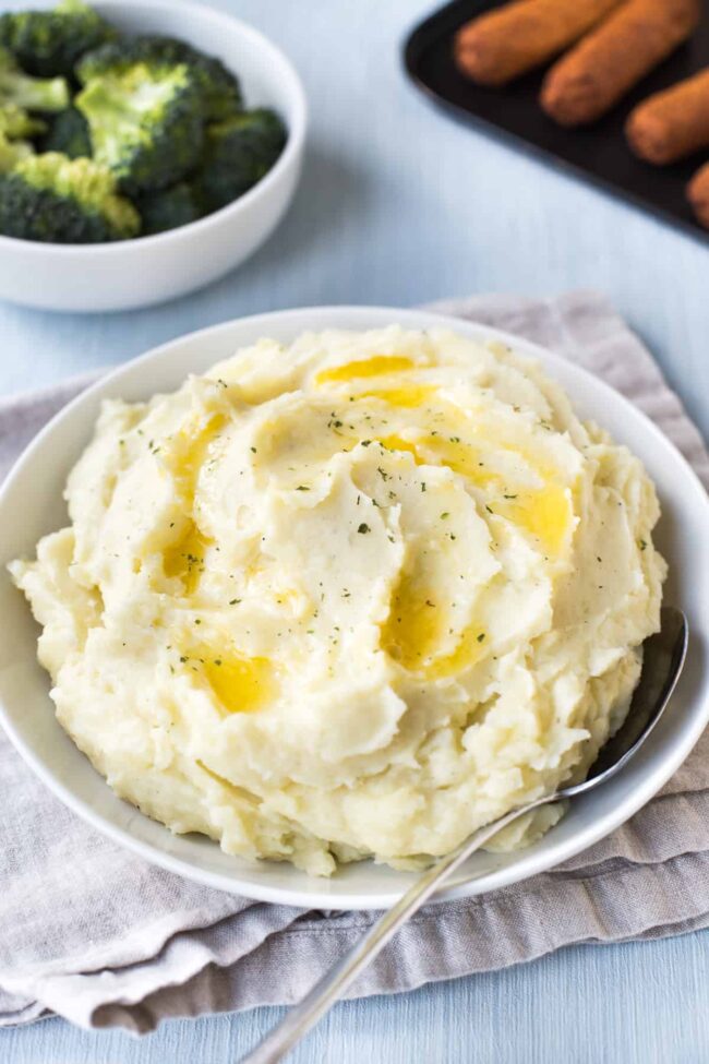 A bowl of creamy mashed potatoes topped with melted butter.