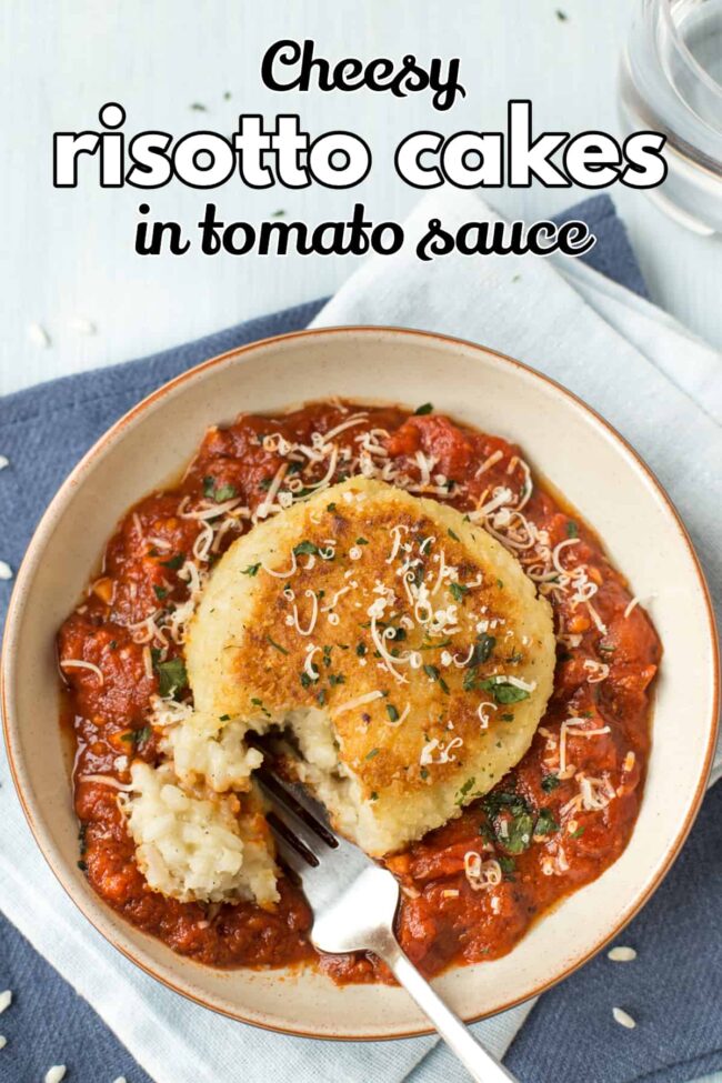 Cheesy risotto cake served on tomato sauce, being broken into with a fork.