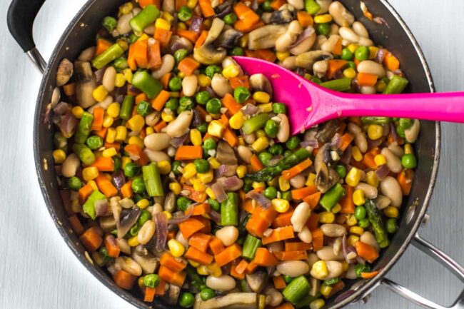 A colourful mixture of different vegetables cooking in a frying pan.