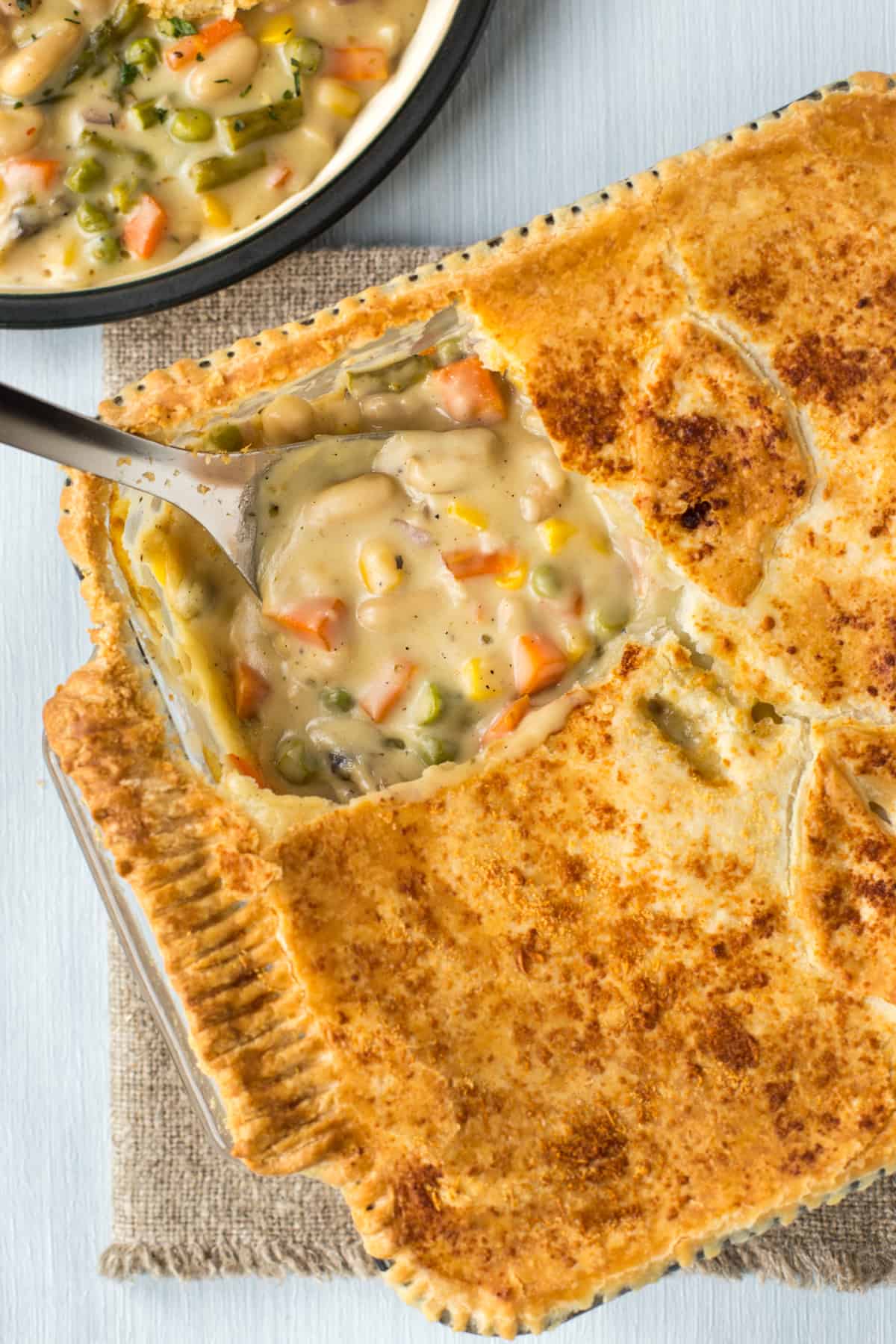 A cheesy vegetable pie in a baking dish with a big scoop being taken.
