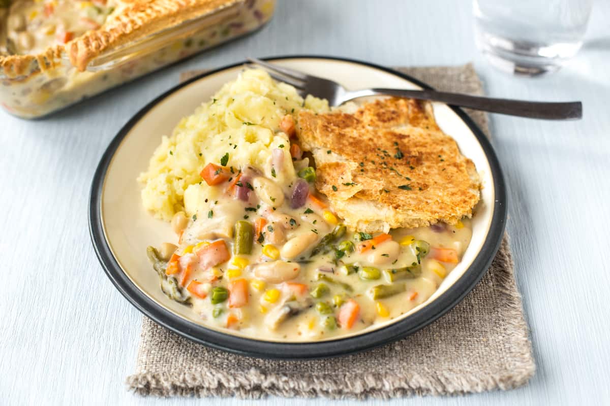 A portion of cheesy vegetable pie on a plate with mashed potatoes.