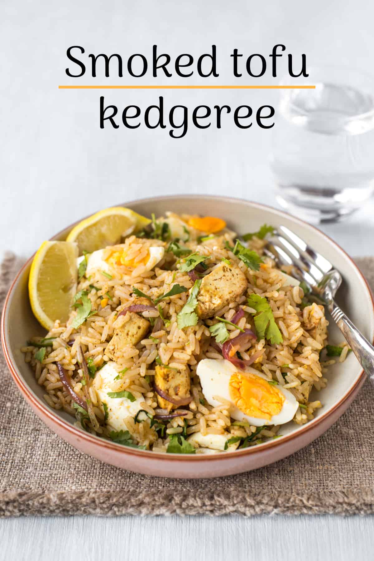 Portion of tofu kedgeree in a bowl with lemon and parsley.