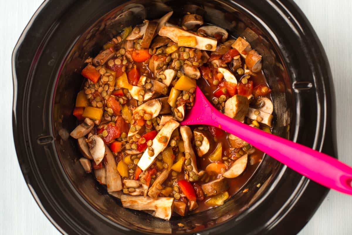 Uncooked lentils and vegetables in a slow cooker.