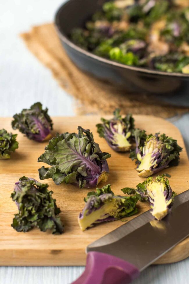 Kalettes on a chopping board with some cut in half.