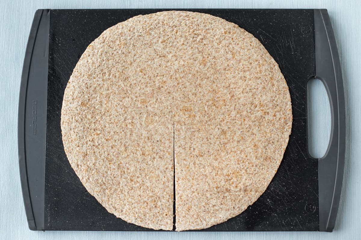 A tortilla on a chopping board with a slit cut.