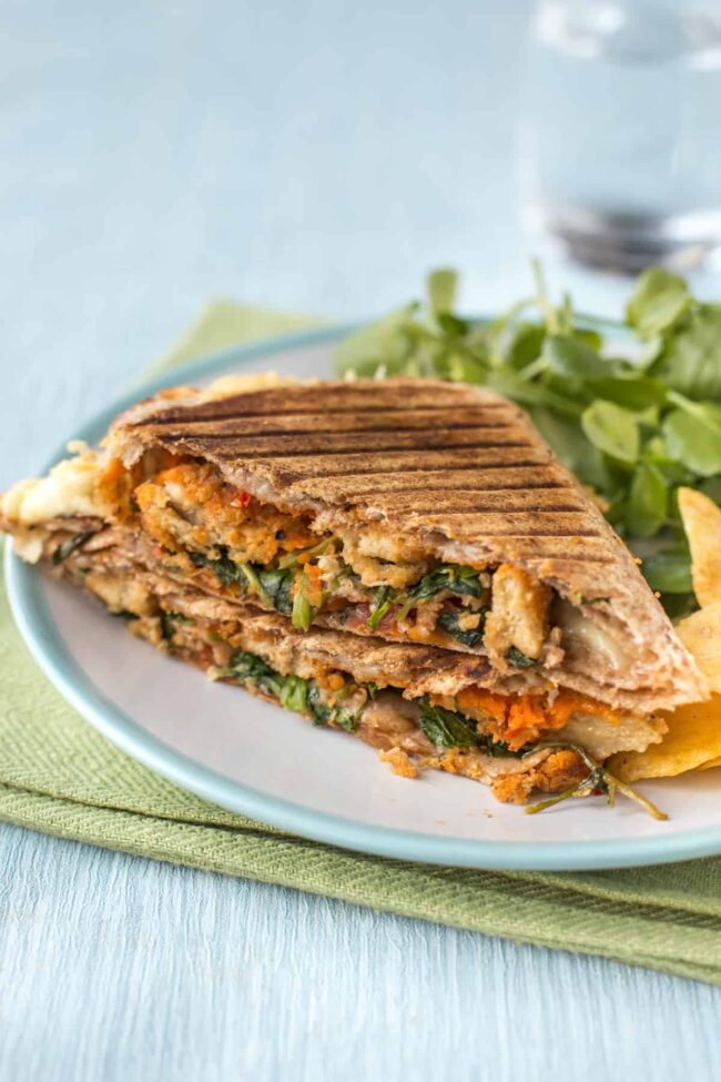 A grilled layered tortilla stuffed with nuggets, watercress, cheese and hummus.