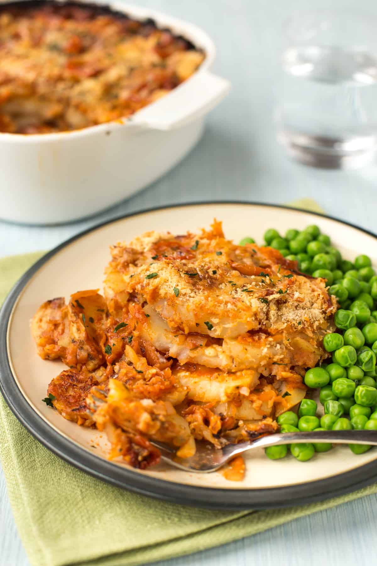 A portion of cheese and tomato potato bake being scooped with a fork.