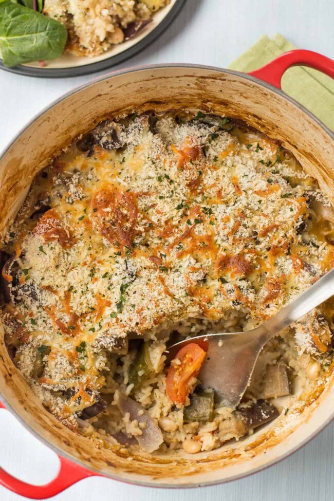 Rice and vegetable casserole in a large casserole dish, with a scoop taken.