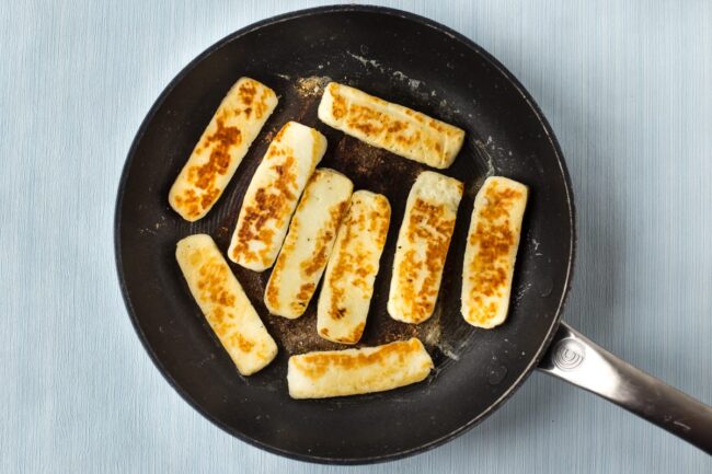 Crispy golden fried halloumi in a frying pan.