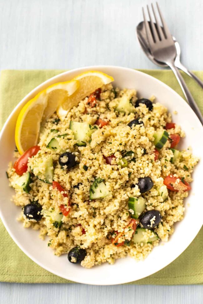 Couscous salad with black olives, cucumbers, tomatoes, and lemon slices.