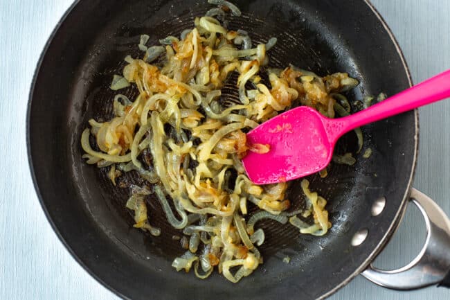 Fried onions cooking in a frying pan.