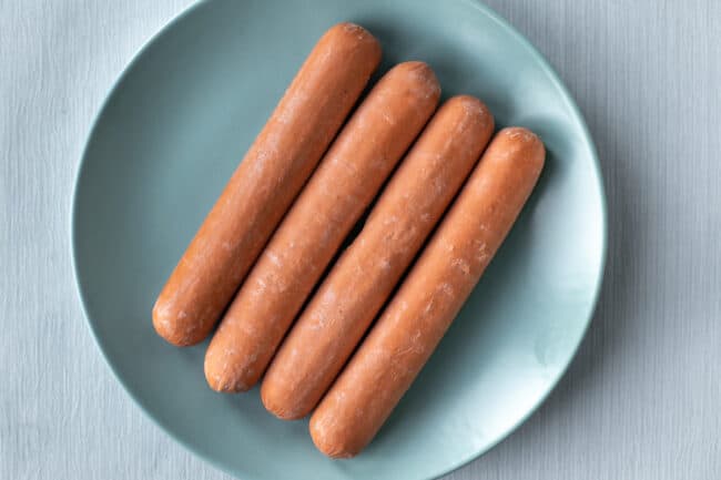Four vegetarian hot dogs on a plate.