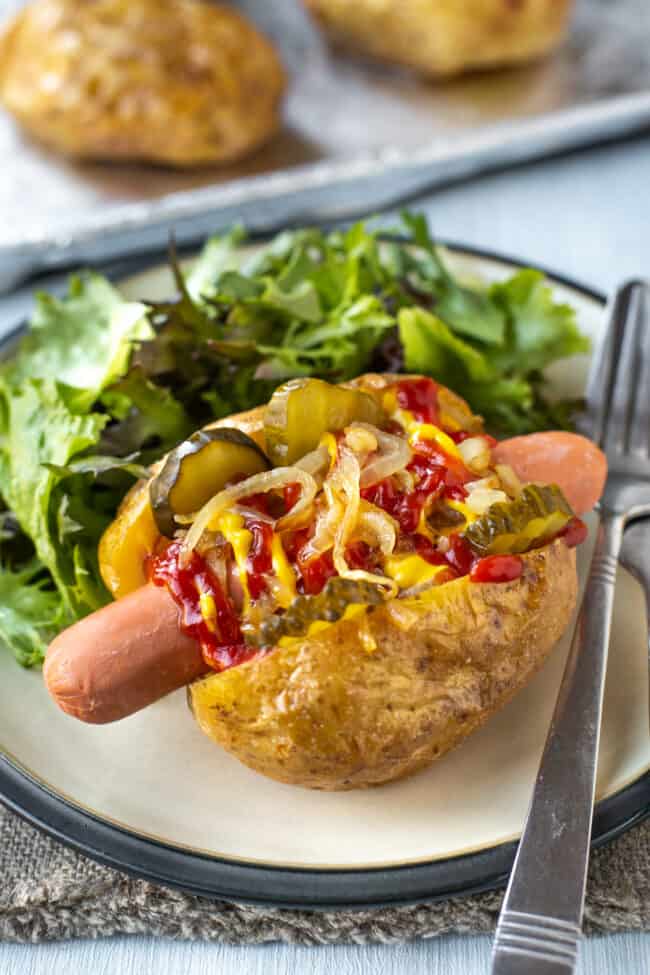 Hot dog jacket potatoes stuffed with hot dog toppings.