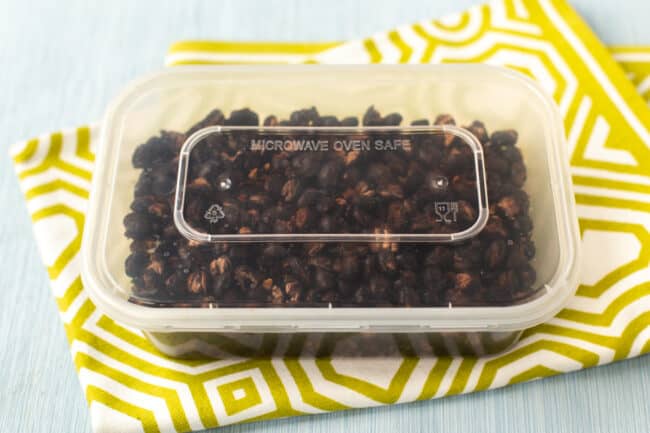 Crispy roasted black beans in a plastic tub.