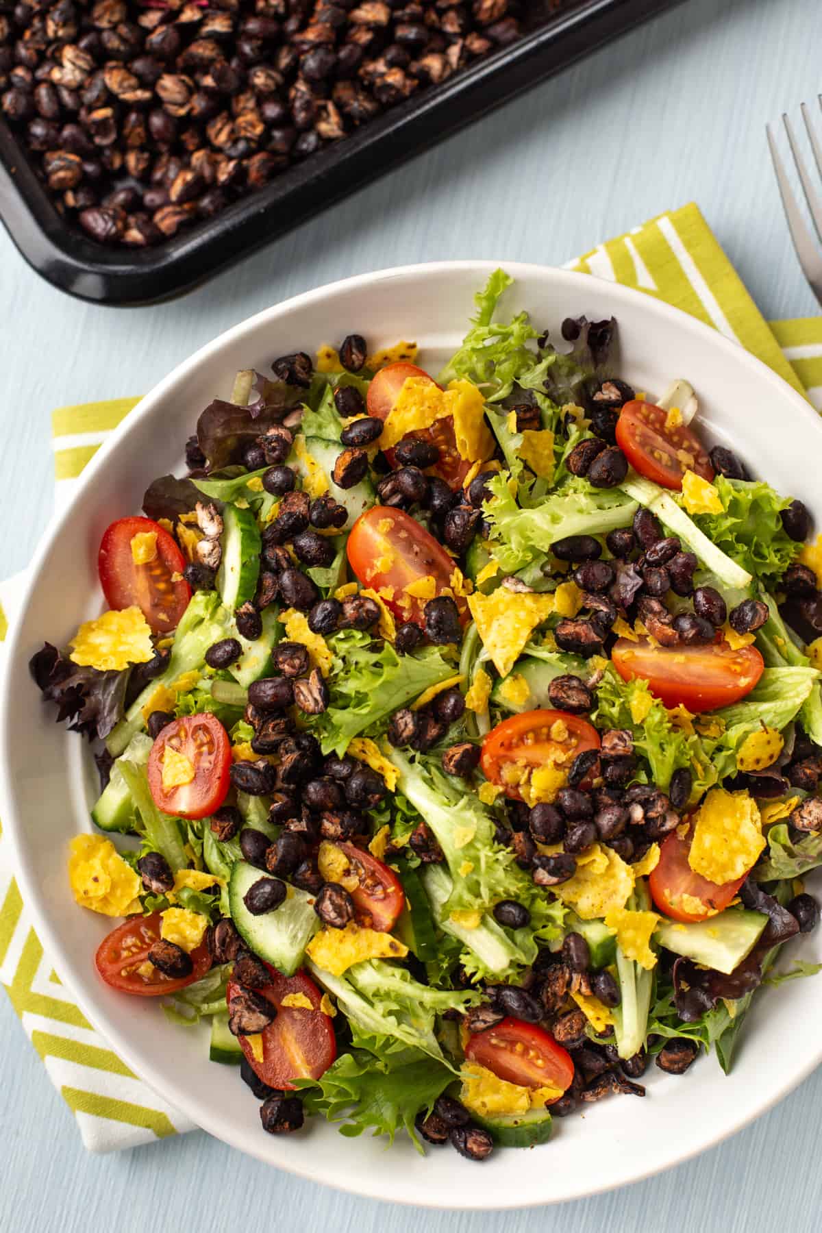 A simple salad with tomatoes and cucumber, topped with roasted black beans.