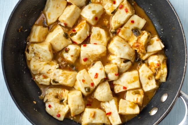 Chunks of halloumi cheese cooking in a sticky sauce.