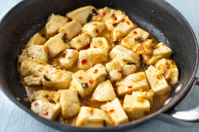 Chunks of halloumi cheese cooking in a sweet and spicy sauce.