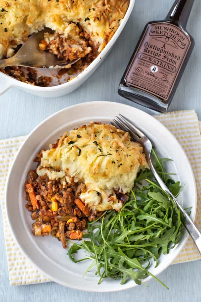 A portion of shepherd's pie in a bowl with fresh arugula.