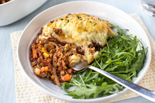 A fork taking a scoop of shepherd's pie from a plate.