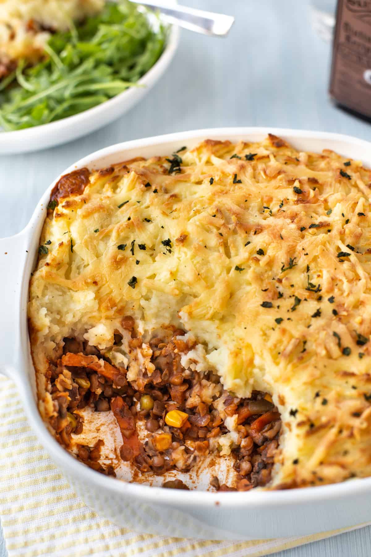 Vegetarian cottage pie in a dish with a large scoop removed.