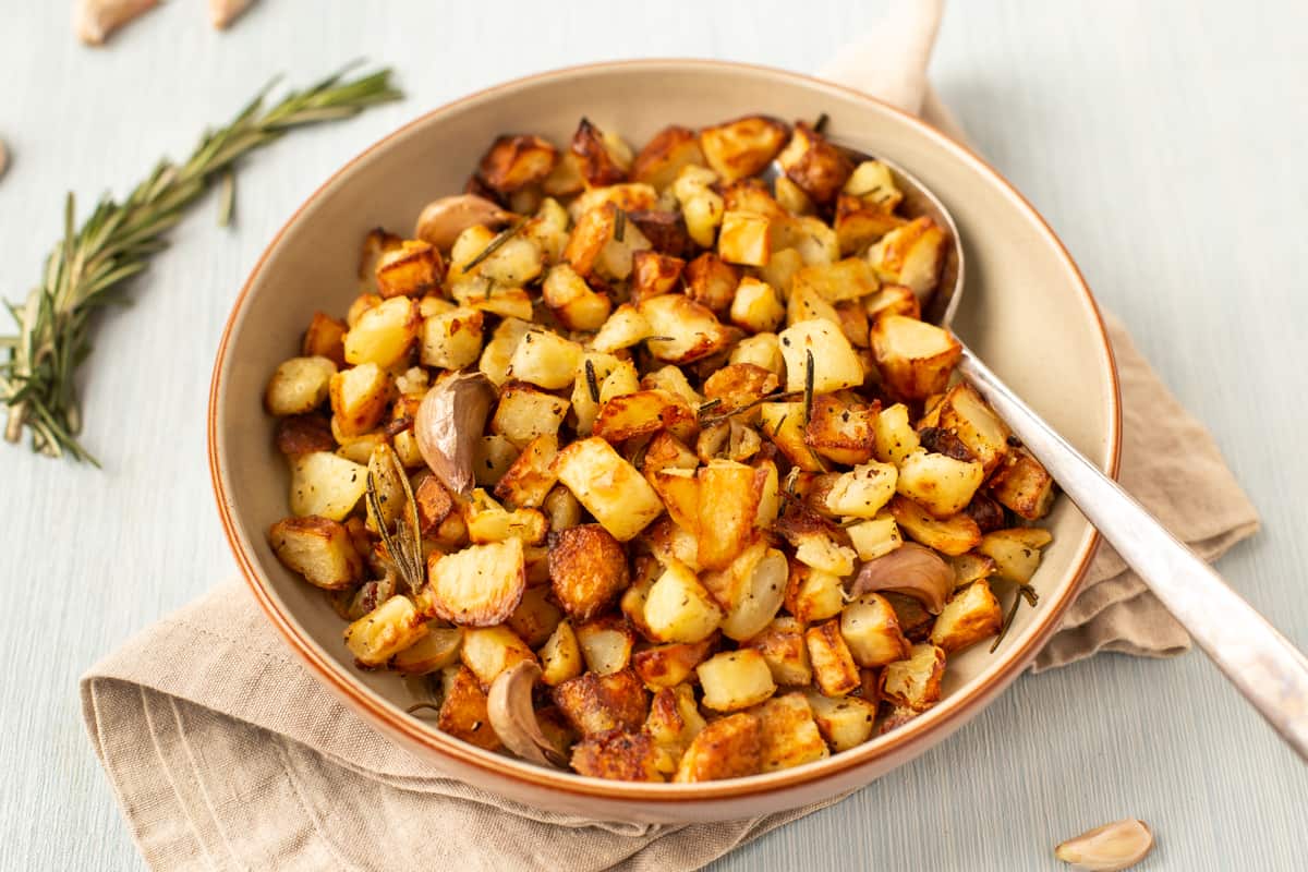 A bowl of crispy Parmentier potatoes with fresh rosemary and garlic.