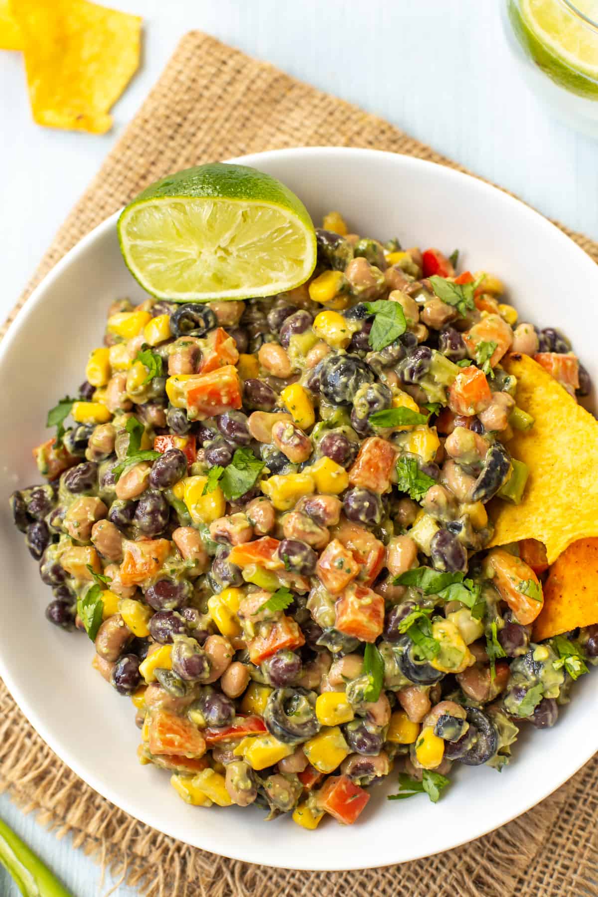 A bowlful of creamy cowboy caviar with fresh lime and tortilla chips on the side.