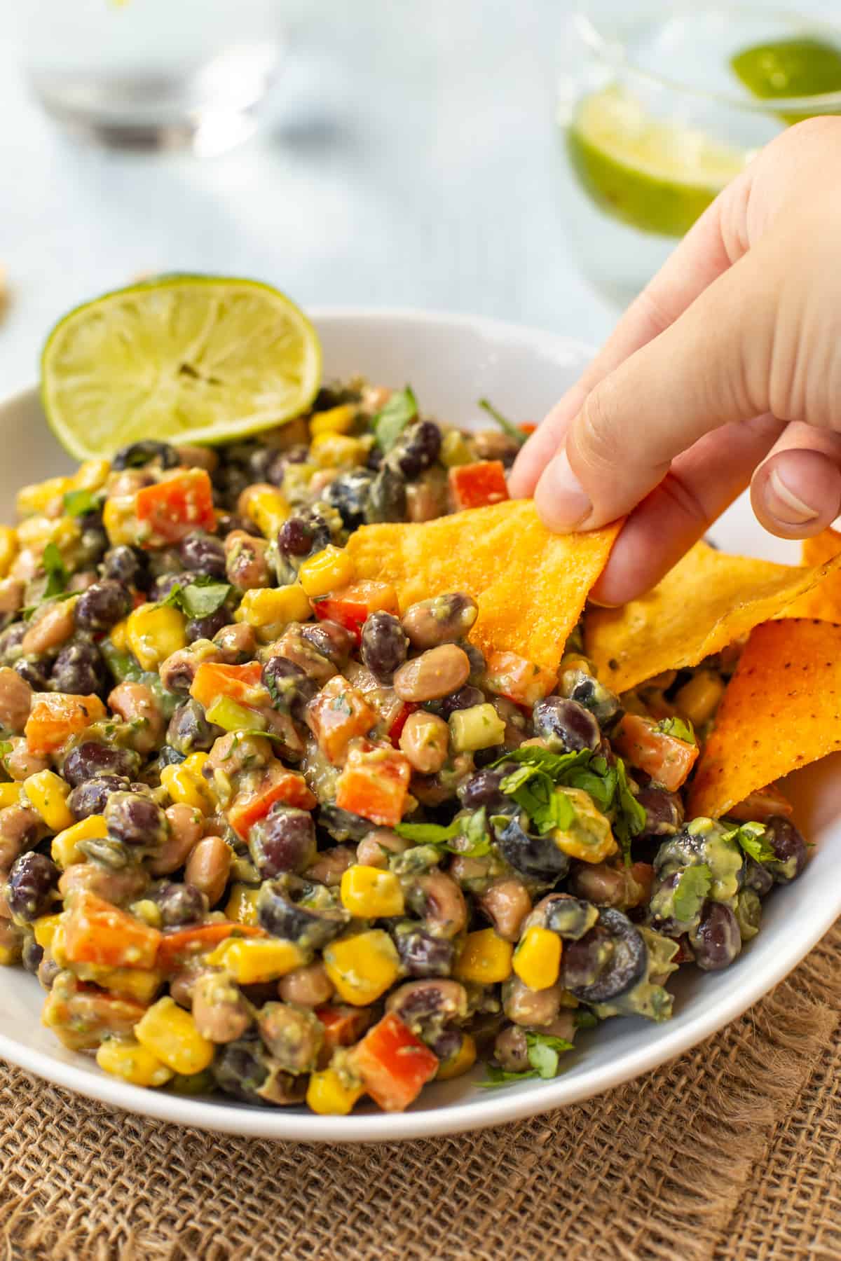 A hand using a tortilla chip to scoop up some cowboy caviar.