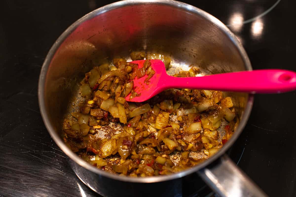 Chopped onion and spices cooking in a saucepan.