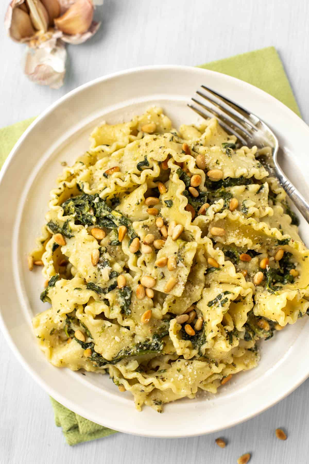 A bowl of mafalde pasta with spinach and pine nuts.