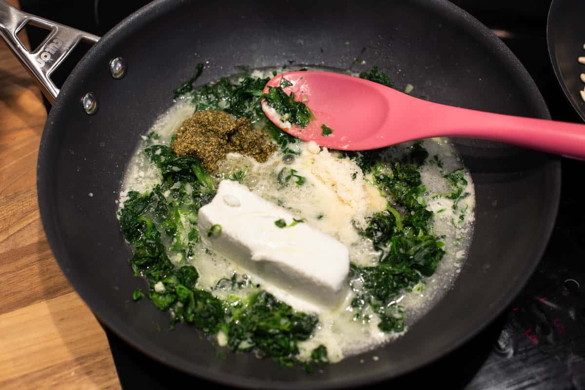 Soft goat cheese and spinach cooking in a frying pan.