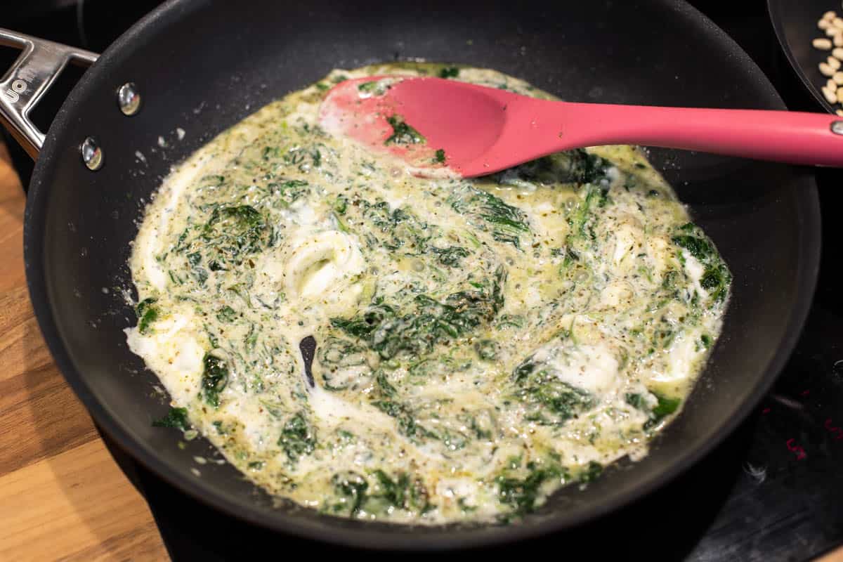 Creamy goat cheese and spinach sauce in a frying pan.