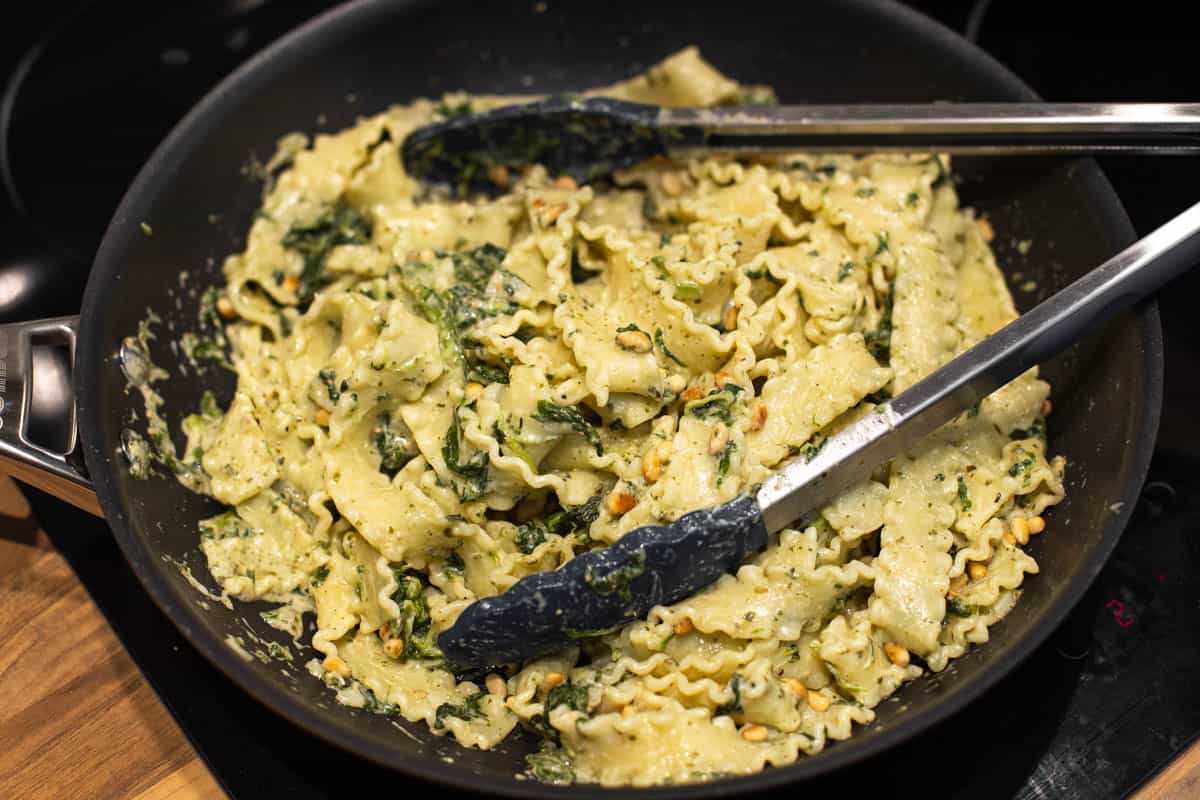 Mafalde pasta tossed in a creamy spinach sauce in a frying pan.