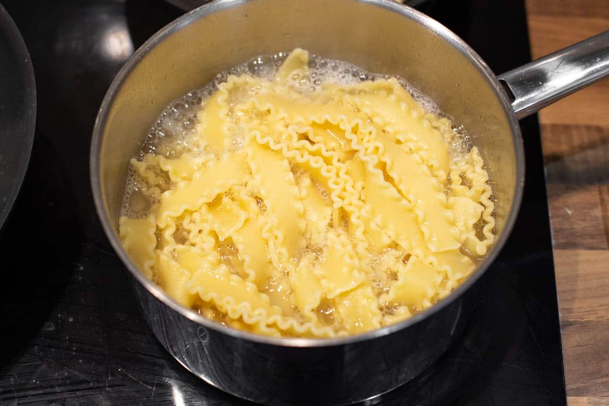 Mafalde pasta cooking in a pan of boiling water.