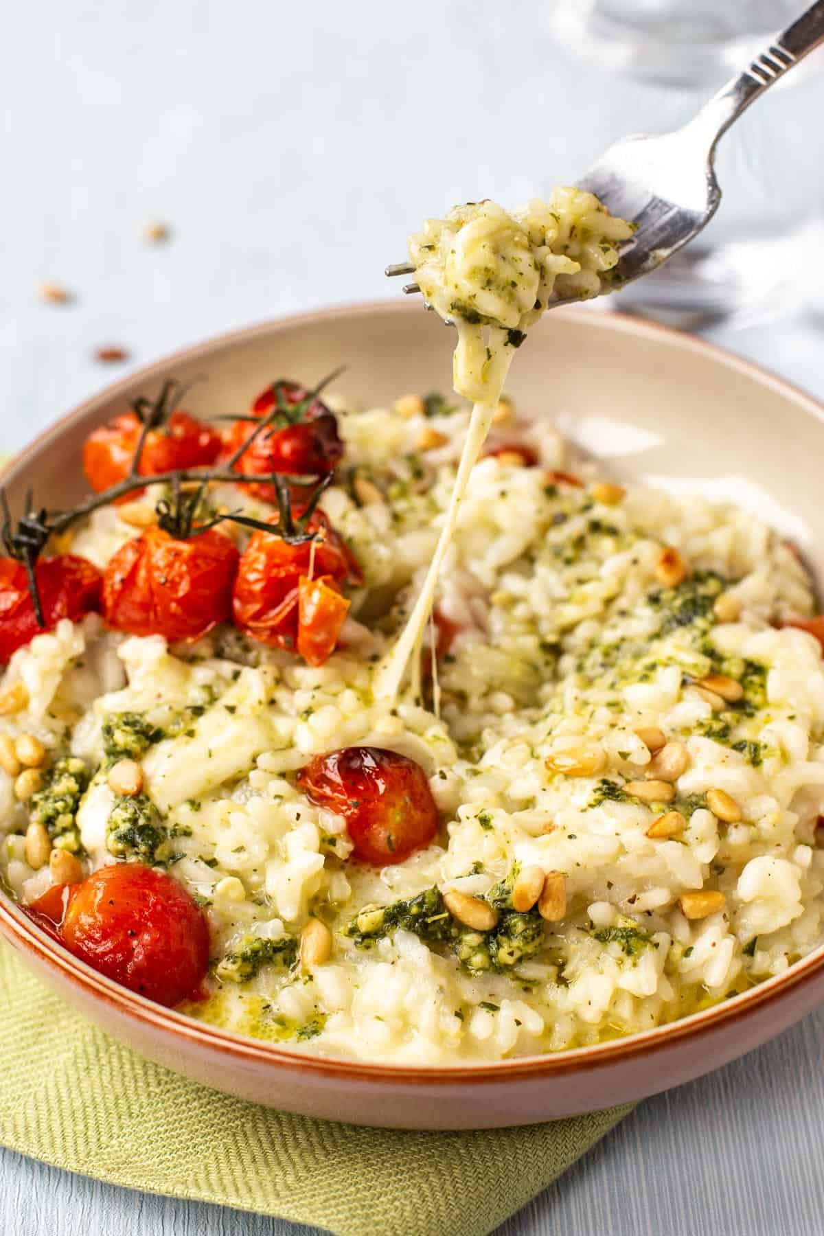A fork taking a scoop of a cheesy caprese risotto.