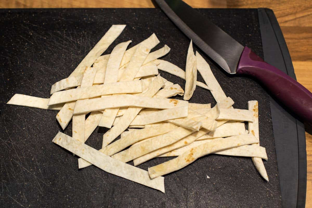 A flour tortilla cut into strips on a chopping board.
