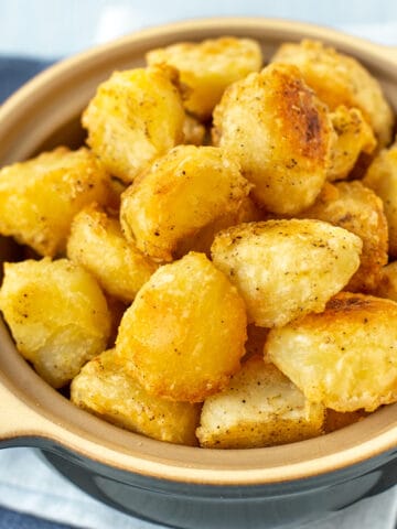 A serving bowl full of crispy roast potatoes.