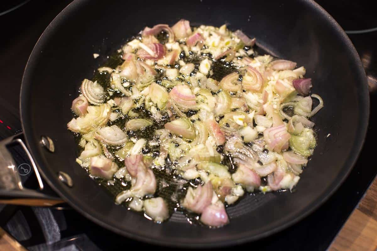 Chopped shallots and garlic cooking in a frying pan.