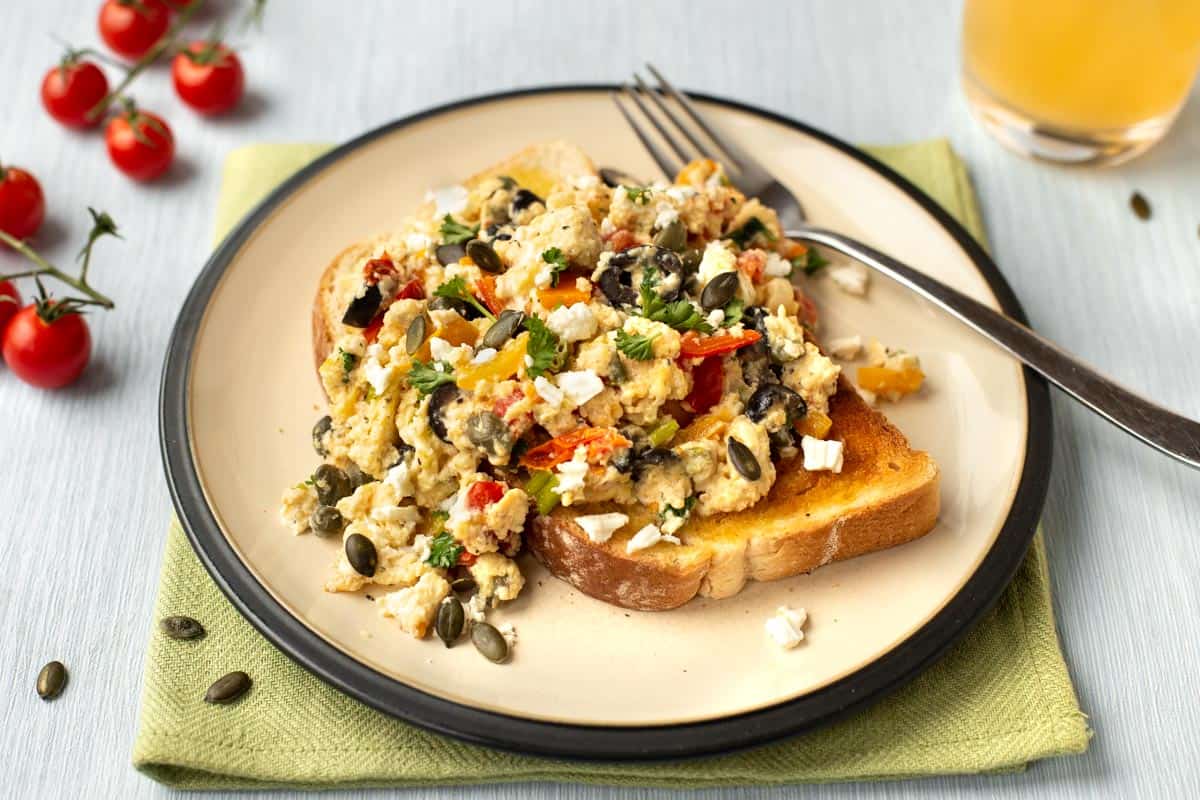 Mediterranean scrambled eggs with feta cheese and olives on a plate.