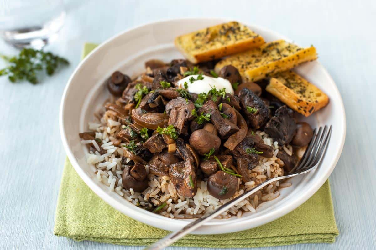 Mushroom stroganoff in a bowl with rice and garlic bread.