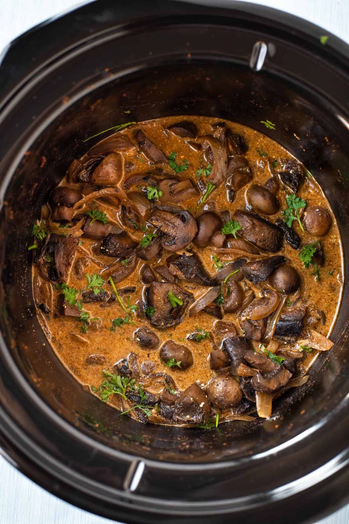 Mushroom stroganoff in a slow cooker with fresh parsley.