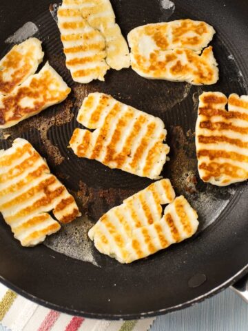 Crispy fried halloumi in a frying pan.