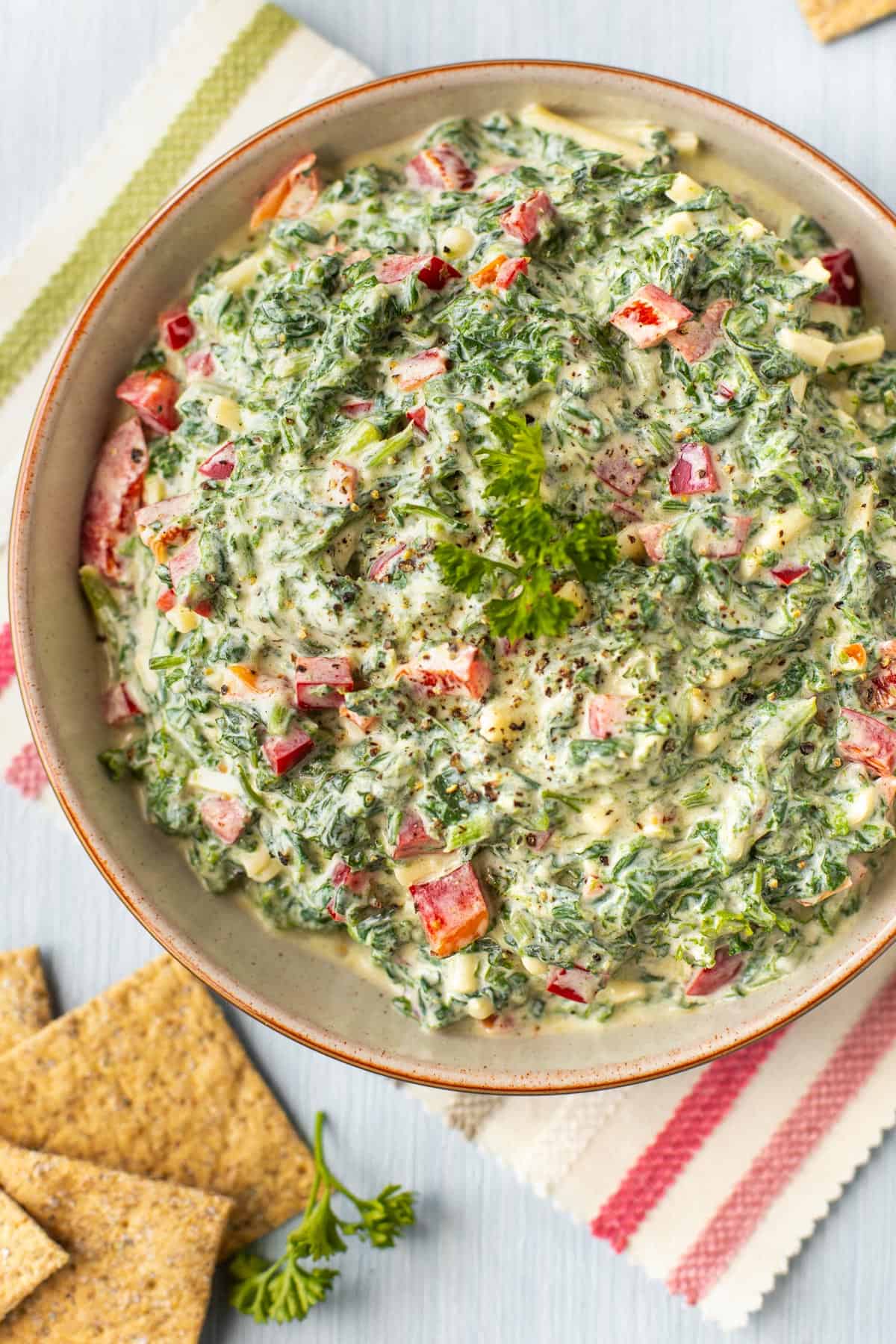 Creamy cold spinach dip in a bowl topped with fresh parsley.