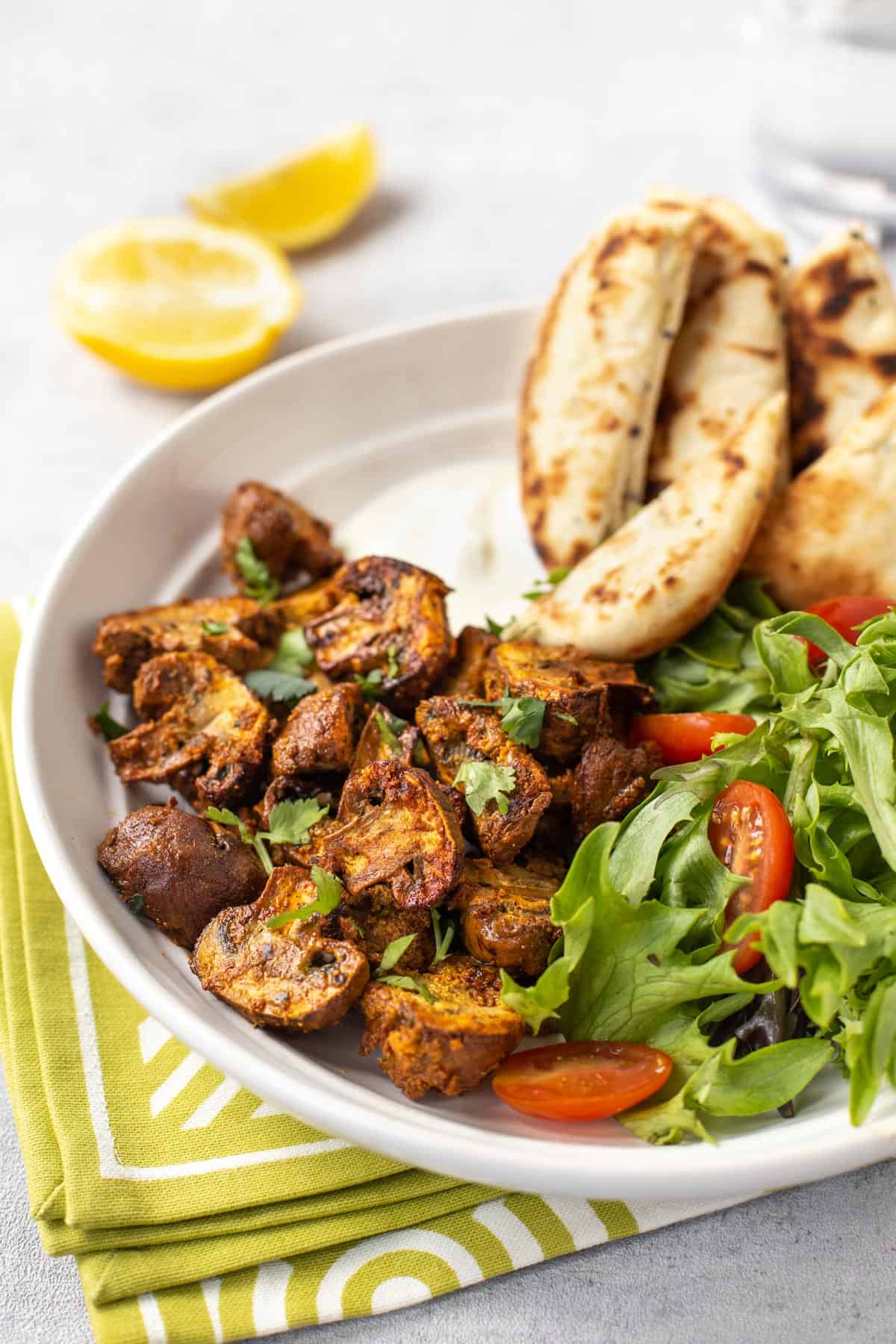 Mushroom tikka in a bowl with naan bread and salad.