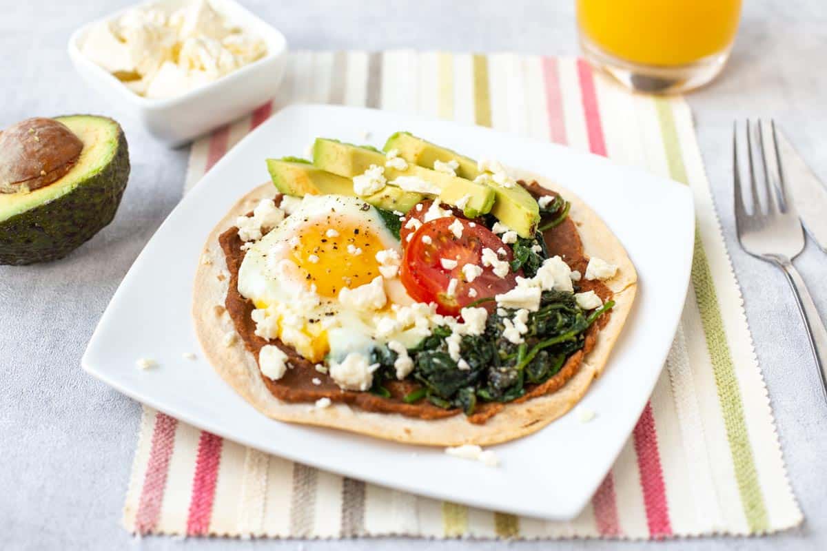 A breakfast tostada with a fried egg and tomatoes.