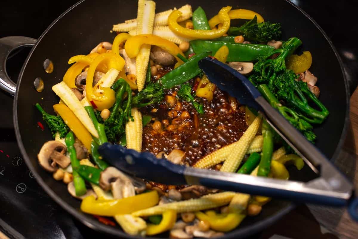 Stir fry vegetables in a wok with soy sauce bubbling in the centre.