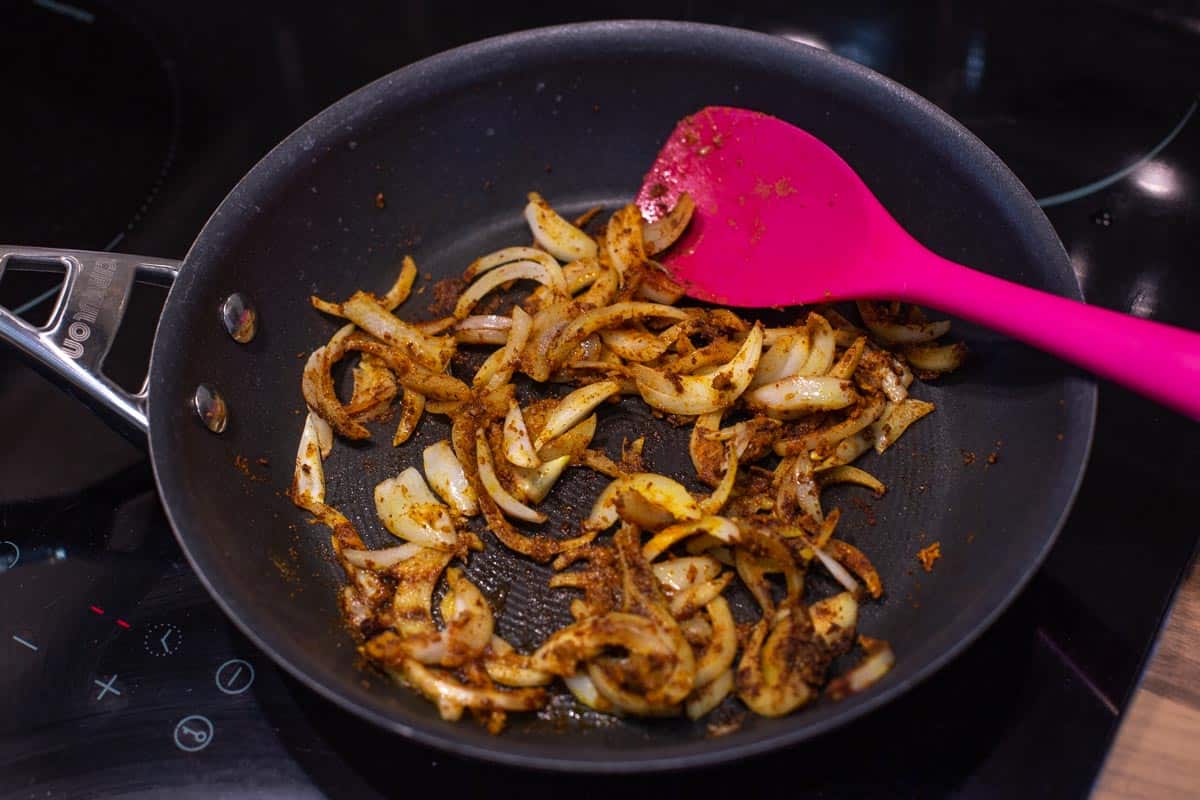 Spiced onions cooking in a frying pan.