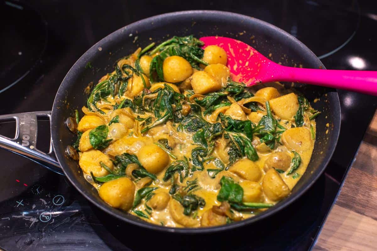 Creamy spinach and potato curry in a frying pan.